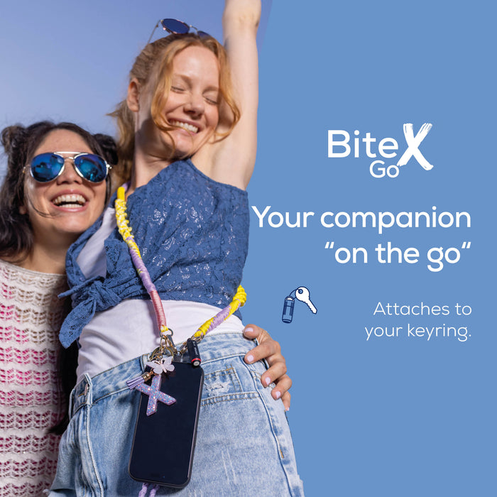 Two smiling women outdoors against a blue sky, with one wearing a colorful keychain phone strap holding a smartphone. The right side has the BiteX Go logo and text reading 'Your companion "on the go"' and 'Attaches to your keyring.