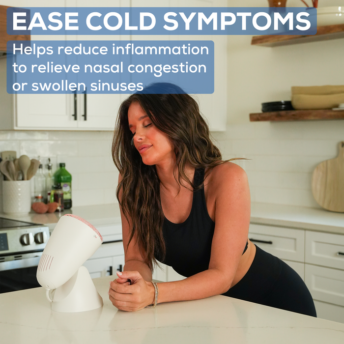 A woman stands at the counter in a bright indoor setting, eyes closed in front of IL11 using it to ease her cold symptoms.   