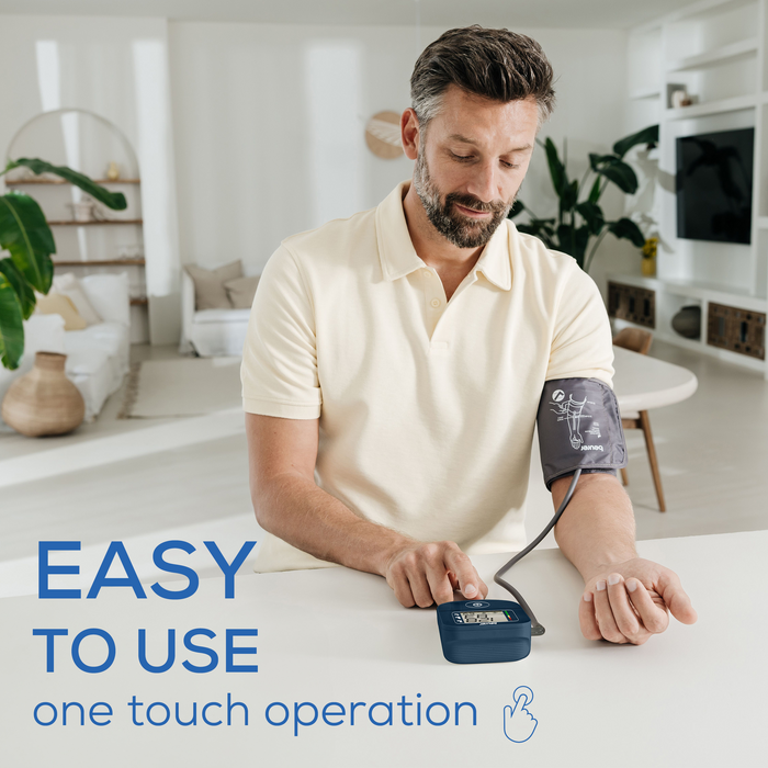 Man using a blood pressure monitor in a living room with text 'EASY TO USE one touch operation'.