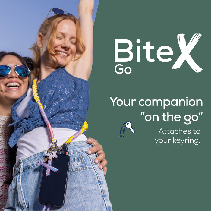 Two smiling women outdoors against a blue sky, with one wearing a colorful keychain phone strap holding a smartphone. The right side has the BiteX Go logo and text reading 'Your companion "on the go"' and 'Attaches to your keyring.