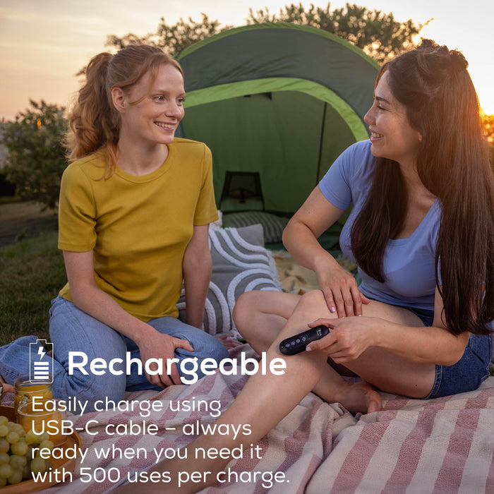 Two women sitting outdoors next to a green tent at sunset, using BiteX Max. Text on the image reads 'Rechargeable' and describes charging via USB-C cable with 500 uses per charge.